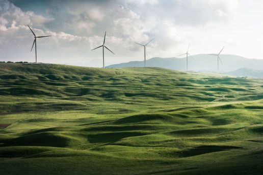 circular economy to save on water, waste, and energy. an image of wind turbines along rolling hills.